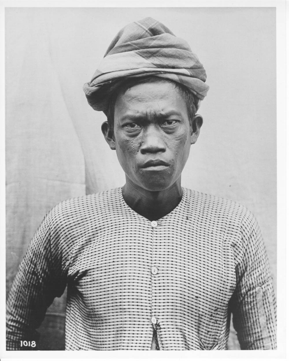<p>Portrait photograph of a Moro man. Number 1018: The number ‘1018’ is written at the lower left-hand corner of the photograph.</p>
