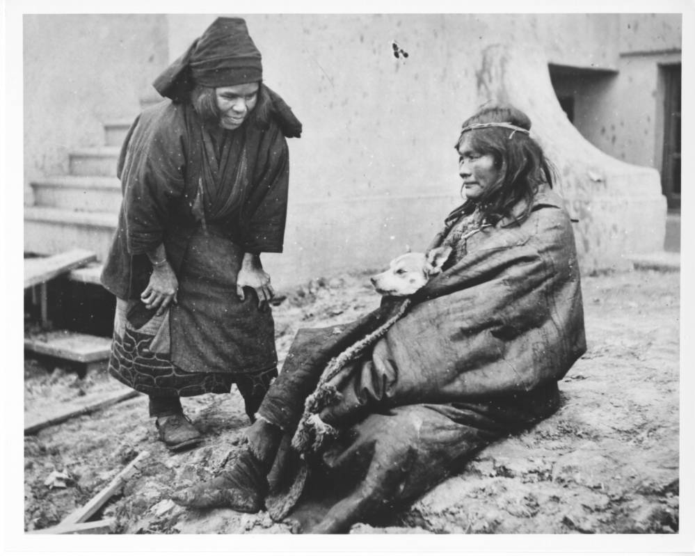 <p>An Ainu woman approaches a seated Patagonian woman, Lorenza, holding her dog Kak within her cloak. Two different women: Imagine what this was like. An Ainu woman from Japan meets a Patagonian woman from Argentina. The Ainu believe that hair growth is a sign of grace. The Patagonians are horsemen. What could these two have in common? How do they communicate?</p>
